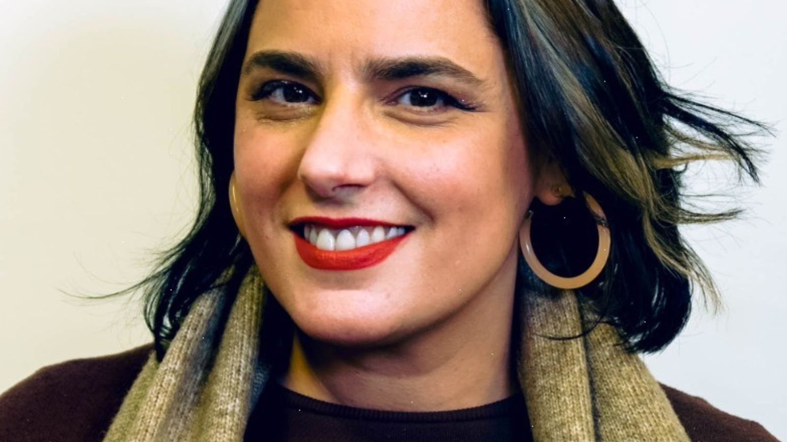 A woman of Scottish and Kuwaiti descent with short black and grey hair wearing black and green, smiling. This is Perth-born Khaleda Noon.