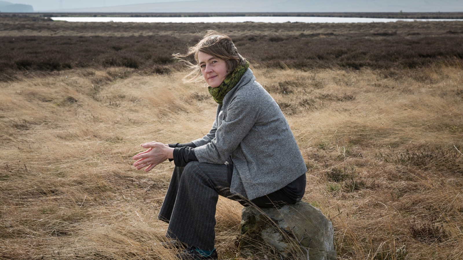 An image of Karine Polwart sat in the Scottish countryside.